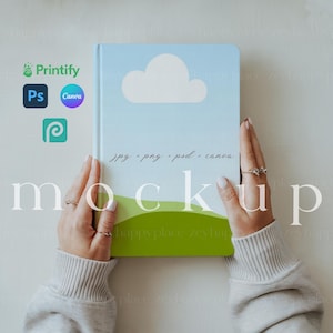 May include: A person is holding a blue notebook with a white cloud on the cover. The notebook has the text "jpg - png - psd - canva" written on it. The text "mockup" is written in white letters on a green and white background.