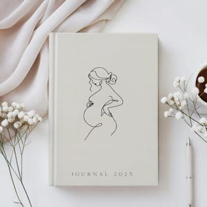 Puede incluir: Un diario blanco con un dibujo lineal de una mujer embarazada en la portada. El texto "JOURNAL 2025" est&aacute; impreso en la parte inferior de la portada.