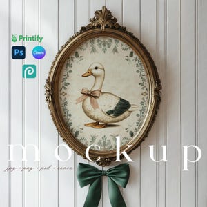 May include: An oval-shaped framed print featuring a duck with a pink bow. The frame is ornate gold, and the print has a vintage aesthetic. A green bow hangs below the frame. The word "mockup" is displayed in large white letters.