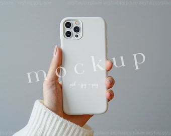 May include: A white iPhone mockup with a white case. The phone is being held in a hand with a white sweater sleeve. The text "mockup" is written in white on the image.