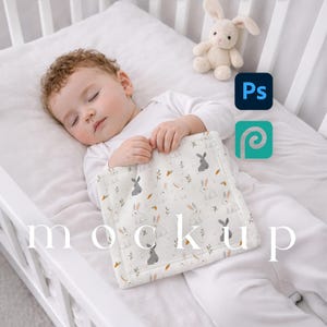 May include: A baby asleep in a white cot, holding a square blanket with a bunny and carrot pattern. A stuffed bunny toy is nearby. The word "mockup" is visible on the blanket.