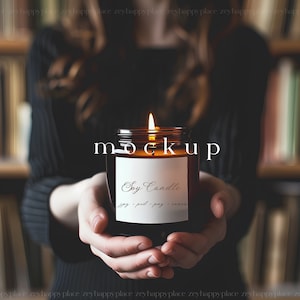 Pu&ograve; includere: Una persona che tiene una candela di soia in vetro marrone con un'etichetta bianca che dice "Soy Candle" e "jpg, psd, pag, canva".
