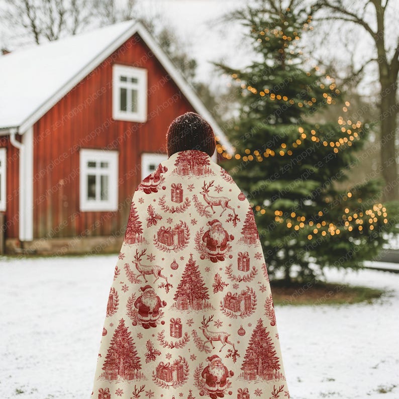 May include: A cream-colored Christmas throw blanket with a red festive pattern featuring Santa Claus, reindeer, Christmas trees, and gift boxes. The blanket is draped over someone standing in a snowy outdoor scene.