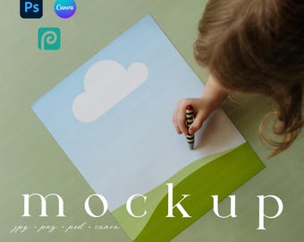 Op de afbeelding: Een mockup-ontwerp met een blauwe lucht, witte wolk en groene heuvels. Het woord "mockup" wordt in grote, witte letters weergegeven. Een kinderhand houdt een krijtje vast, wat een speels element toevoegt. Printify-, Ps- en Canva-logo's zijn zichtbaar.
