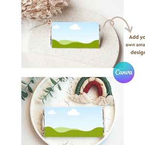 May include: Two images showing a blank printable template for a chocolate bar wrapper. The template features a green grassy field with a blue sky and white clouds. The text "Add your own amazing design!" is written in a white box with a sparkle. The text "Canva" is written in a blue and purple box.