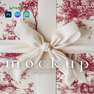 以下が含まれることがあります： クリーム色のリボンとリボンが、赤と白のトワル柄の箱を飾っています。「mockup」という言葉が中央に表示されています。画像には、Printify、Photoshop、Canva、およびデザインツールのロゴも含まれています。