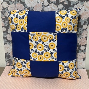 May include: A blue and white pillow with a floral pattern. The pillow is made of fabric and has a square shape.