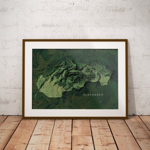 May include: A framed print of Slovakia, showcasing a detailed topographical map in shades of green and brown. The word "SLOVENSKO" is printed in white. The frame is a dark brown color.