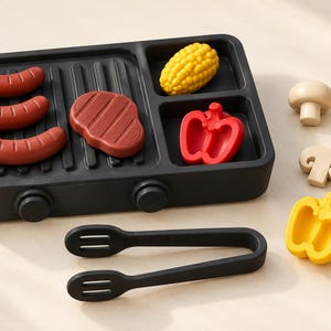 May include: A black toy grill set featuring three brown sausages, a brown steak, a yellow corn cob, and a red bell pepper half on the grill surface. Includes a pair of black tongs, two beige mushrooms, and a yellow bell pepper half.