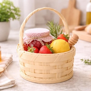 May include: A woven basket filled with a jar of jam, fresh strawberries, and a lemon. A jar of honey and a wooden spoon sit nearby. The basket has a handle and is surrounded by greenery, suggesting a picnic or food-themed presentation.