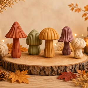 May include: A set of five decorative mushroom figurines in varying shapes and colours, including rust, sage green, mustard yellow, mauve, and cream. Each mushroom features a ribbed, vertical texture on both the cap and the stem, standing upright.