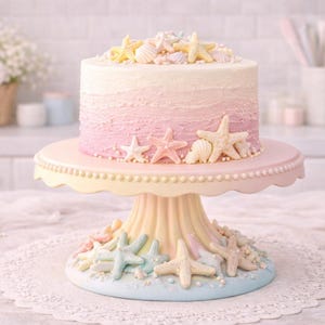 May include: A round cake with a pink and white ombre frosting, decorated with starfish and seashells. The cake sits on a tiered cake stand with a pastel color scheme, featuring starfish and seashell accents. The cake is a dessert.
