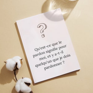 May include: A white card with a question mark drawn on it. The card has text that reads: 'Qu'est-ce que le pardon signifie pour moi, et y a-t-il quelqu'un que je dois pardonner?'