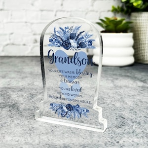 May include: A clear acrylic memorial plaque with a blue floral design and the text "Grandson, Your life was a blessing, Your memory a treasure, You're loved beyond words, missed beyond measure."