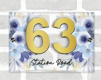 May include: A white glass house number sign with a blue floral design and gold glitter stars. The number 63 is in gold and the text "Station Road" is in black.