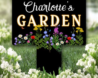 Può includere: Cartello da giardino nero con testo bianco che recita "Charlotte's GARDEN" con un bordo giallo attorno alla parola "GARDEN". Il cartello è decorato con una varietà di fiori e farfalle colorati.