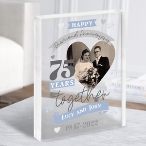 May include: A clear glass block with a heart-shaped photo of an older couple in black and white. The text "HAPPY Diamond Anniversary 75 YEARS together LUCY AND JOHN 1947-2022" is printed on the block.