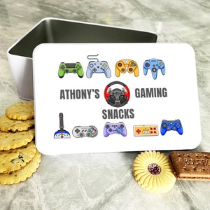 Op de afbeelding: Witte metalen doos met een kleurrijk ontwerp van videogamecontrollers en de tekst "Athony's Gaming Snacks".