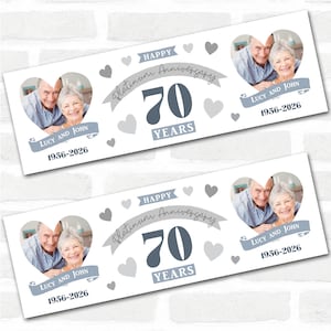 May include: Two white rectangular cards with a 70th anniversary theme. Each card features a photo of a couple in a heart shape, the text "Happy Platinum Anniversary 70 Years", and the names "Lucy and John" with the years 1956-2026.