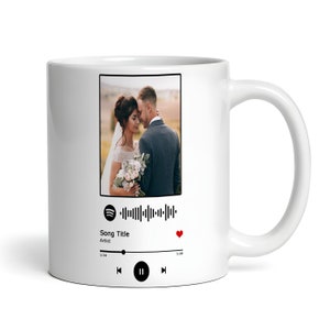 May include: White ceramic mug with a photo of a couple in a wedding setting. The mug has a Spotify-like music player design with a barcode, song title, artist, and play controls.