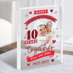 Könnte beinhalten: Ein weißer Acrylblock mit einem roten Herzdesign, das einen 40. Hochzeitstag feiert. Der Text lautet "Happy Ruby Anniversary 40 Years Together Lucy and John 1972-2022". Ein Foto eines Paares befindet sich im Herzen.