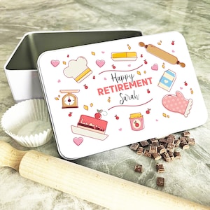May include: White metal tin with a colorful design of baking items and the text "Happy Retirement Sarah".