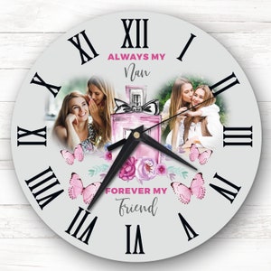 Puede incluir: Reloj blanco con números romanos y una aguja negra. La esfera del reloj presenta dos fotos de mujeres, un frasco de perfume rosa y mariposas rosas. El texto "Always My Nan" y "Forever My Friend" está impreso en la esfera del reloj.