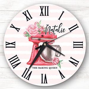 May include: A pink and white striped clock with Roman numerals. The clock features a red stand mixer with a floral design and the text "The Baking Queen". The name "Natalie" is written in cursive on the clock face.