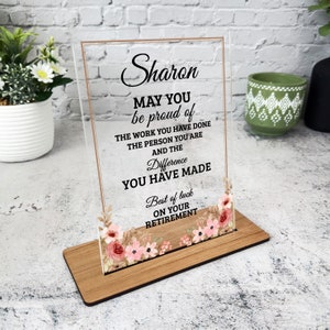 Puede incluir: Una placa de acrílico transparente con un diseño floral y el texto "Sharon MAY YOU be proud of THE WORK YOU HAVE DONE THE PERSON YOU ARE AND THE Difference YOU HAVE MADE Best of luck ON YOUR RETIREMENT".