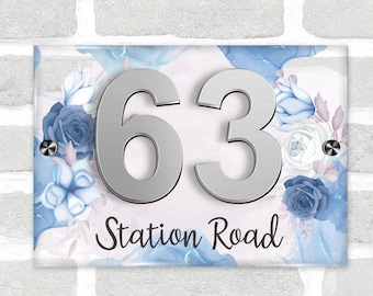 May include: A blue and white floral design house number plaque with silver numbers "63" and the text "Station Road".