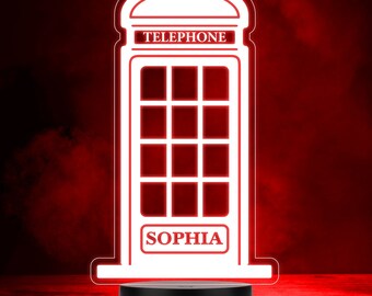May include: A white silhouette of a red telephone booth with the word "TELEPHONE" above a window and the name "SOPHIA" below the window. The silhouette is on a black base.