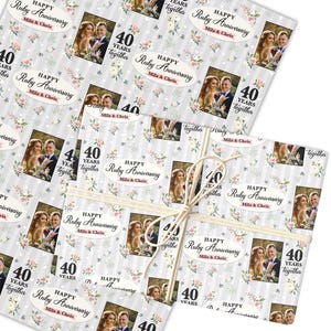 Puede incluir: Dos rollos de papel de regalo con un patrón repetido de fotos, detalles florales y texto. El texto dice "HAPPY Ruby Anniversary Mila & Chris" y "40 YEARS together". Los rollos están atados con hilo.