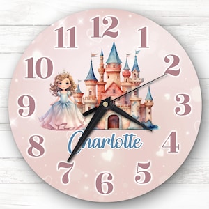 Puede incluir: Reloj rosa con temática de princesa con una princesa de dibujos animados y un castillo. La esfera del reloj tiene números rosas y una aguja de reloj negra. El nombre "Charlotte" está escrito en azul debajo del castillo.