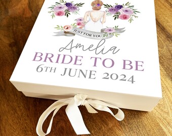 Pode incluir: Caixa de presente branca com um design floral roxo e rosa, uma silhueta de noiva e o texto "Just for you", "Amelia Bride to Be" e "6th June 2024".