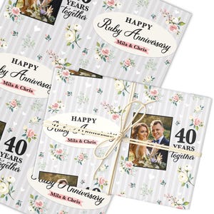 Puede incluir: Papel de regalo con un diseño floral y el texto "Happy Ruby Anniversary Mila & Chris". El envoltorio presenta una foto de una pareja y las palabras "40 Years Together". El diseño incluye flores blancas y rosas.