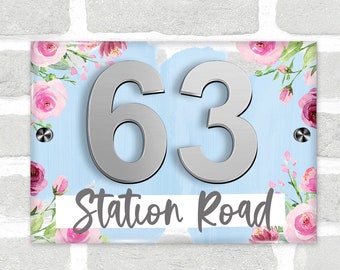 May include: A blue and pink floral house number sign with the number 63 and the text "Station Road".