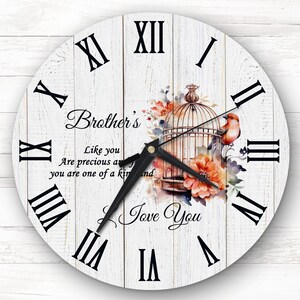 May include: A white wooden clock with Roman numerals and a black clock hand. The clock face features a watercolor illustration of a bird in a cage with flowers. The text "Brother's" and "Like you are precious and you are one of a kind" is written on the clock face. The text "Love You" is written below the birdcage.