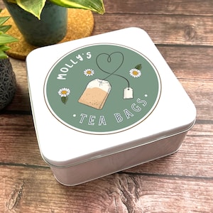 May include: White square tin with a green circle design. The circle has the text "Molly's Tea Bags" and a drawing of a tea bag with a heart-shaped string.
