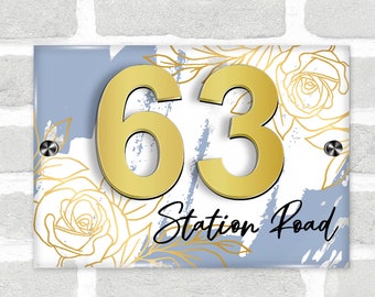 May include: A blue and white house number sign with gold floral accents and the number 63. The sign also includes the text "Station Road" in black.