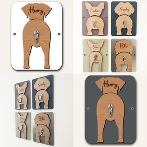 May include: Set of six wooden dog butt-shaped hooks with names engraved on each. The hooks are in various colors, including white, gray, brown, and green. The hooks are designed to hang on a wall and can be used to hang leashes, collars, or other dog accessories.