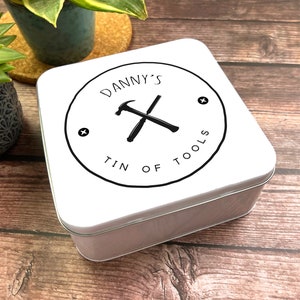 May include: White square tin with a black and white logo. The logo is a circle with the text "DANNY'S TIN OF TOOLS" and a crossed hammer and screwdriver.