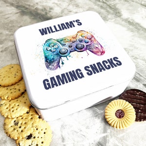 Op de afbeelding: Witte vierkante blik met een kleurrijke aquarel-illustratie van een videogamecontroller. De tekst "WILLIAM'S GAMING SNACKS" staat op de blik gedrukt.