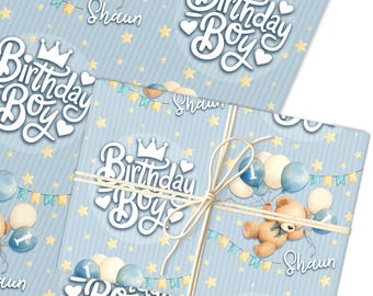 May include: Light blue wrapping paper with a repeating pattern of yellow stars and a teddy bear holding balloons. The words "Birthday Boy" are in a white script font, and the name "Shaun" is also visible.