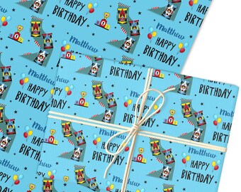 May include: Two gift-wrapped presents with a light blue background. The wrapping paper features a race car theme with race cars, trophies, balloons, and the text "Matthew HAPPY BIRTHDAY". The gifts are tied with a natural twine.