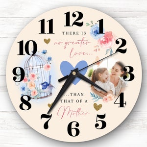 May include: A cream-colored clock with black numbers and hands. The clock has a floral design with a blue bird in a cage and a photo of a mother and child. The text on the clock reads "There is no greater love... than that of a Mother."