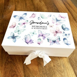 May include: White keepsake box with a butterfly design and the text "Grandma's Memories & Keepsakes". The box has a white satin ribbon.
