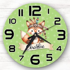 May include: A green and white clock with a fox wearing a headdress and a banner that says "charlie". The clock has black numbers and a star pattern.