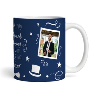 Può includere: Una tazza in ceramica blu con manico bianco. La tazza ha un design bianco con stelle, volute e un cappello a cilindro. La tazza presenta anche una foto di un uomo in abito e cravatta. Il testo sulla tazza recita "Grazie per essere il padre più fantastico".