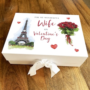 May include: White gift box with a red ribbon. The box has a printed design featuring the Eiffel Tower, a bouquet of red roses, and the text "For my wonderful Wife on Valentine's Day".