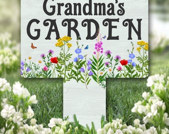 Può includere: Un cartello da giardino in legno bianco con il testo "Grandma's GARDEN" in lettere nere. Il cartello è decorato con un bordo di fiori selvatici colorati e farfalle.